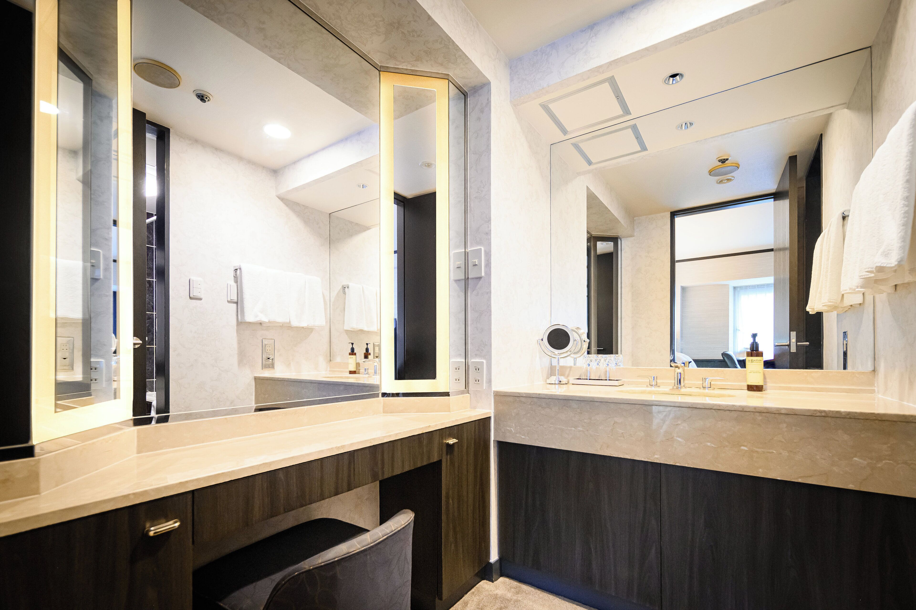 A modern bathroom with two sinks, large mirrors, and a vanity with a towel rack.