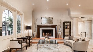 A spacious living room with a fireplace, large windows, and a comfortable seating area. - Montecito Inn (Santa Barbara)