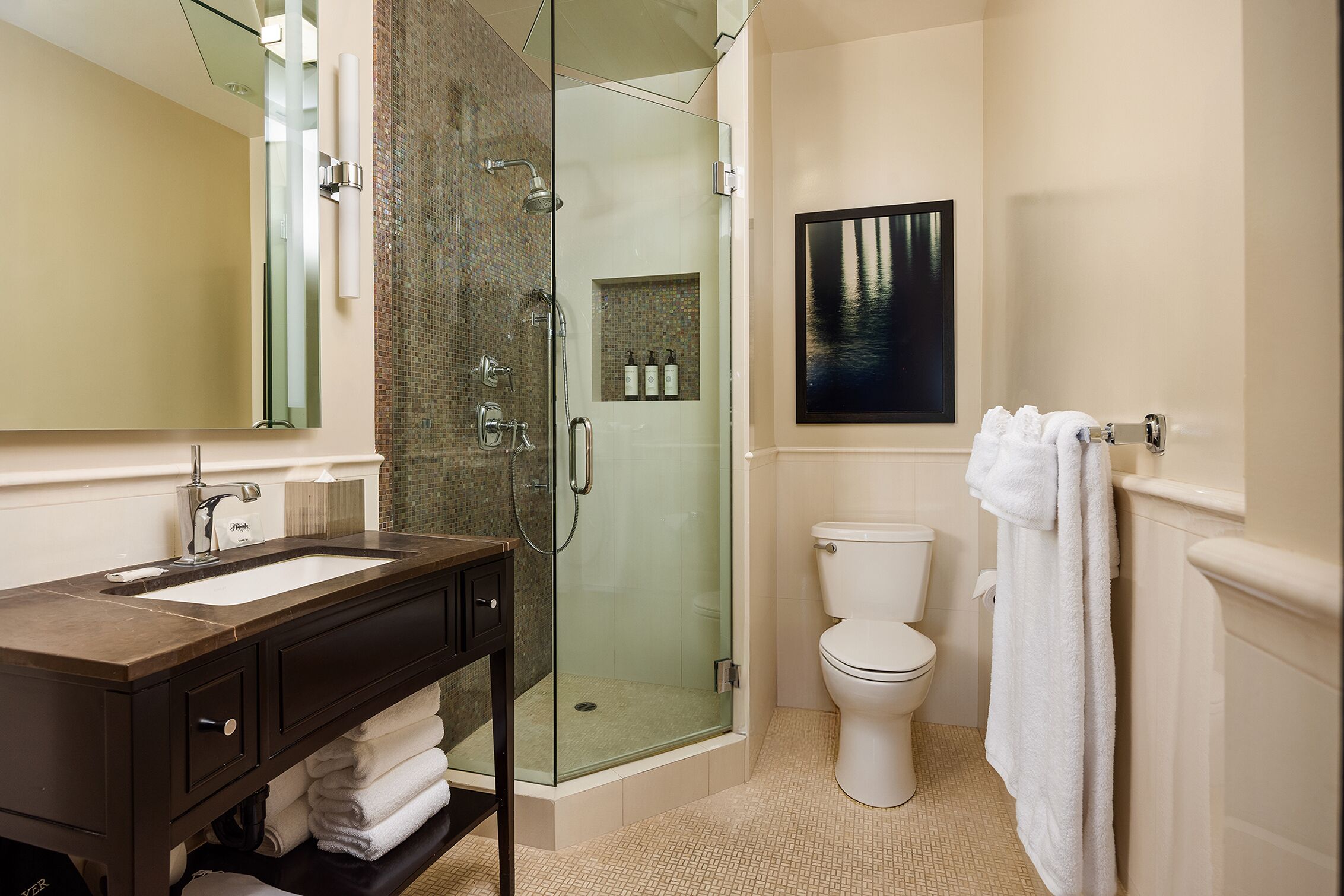 Un bagno moderno con doccia vetrata, un WC bianco, uno specchio grande e un lavandino con piano d'appoggio scuro.