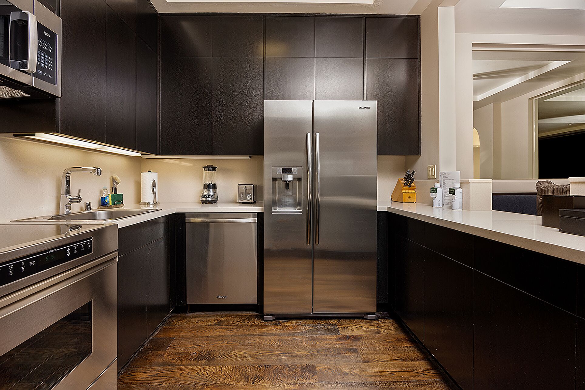 A modern kitchen with a stainless steel refrigerator, a built-in dishwasher, and a coffee maker.