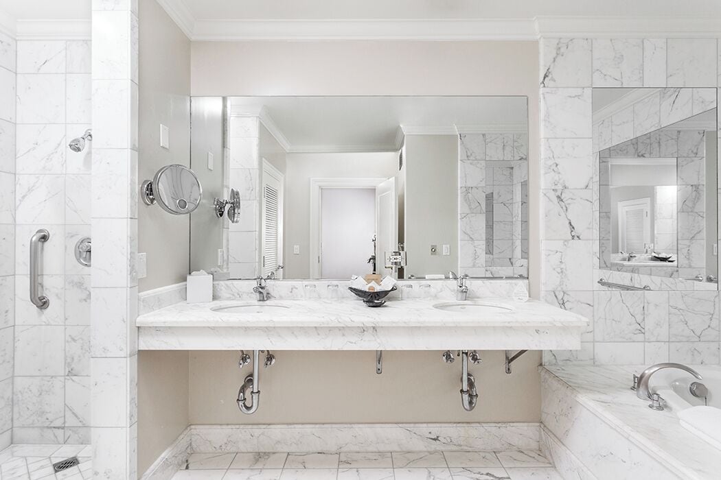 A bathroom with a large marble sink, two mirrors, and a bathtub.