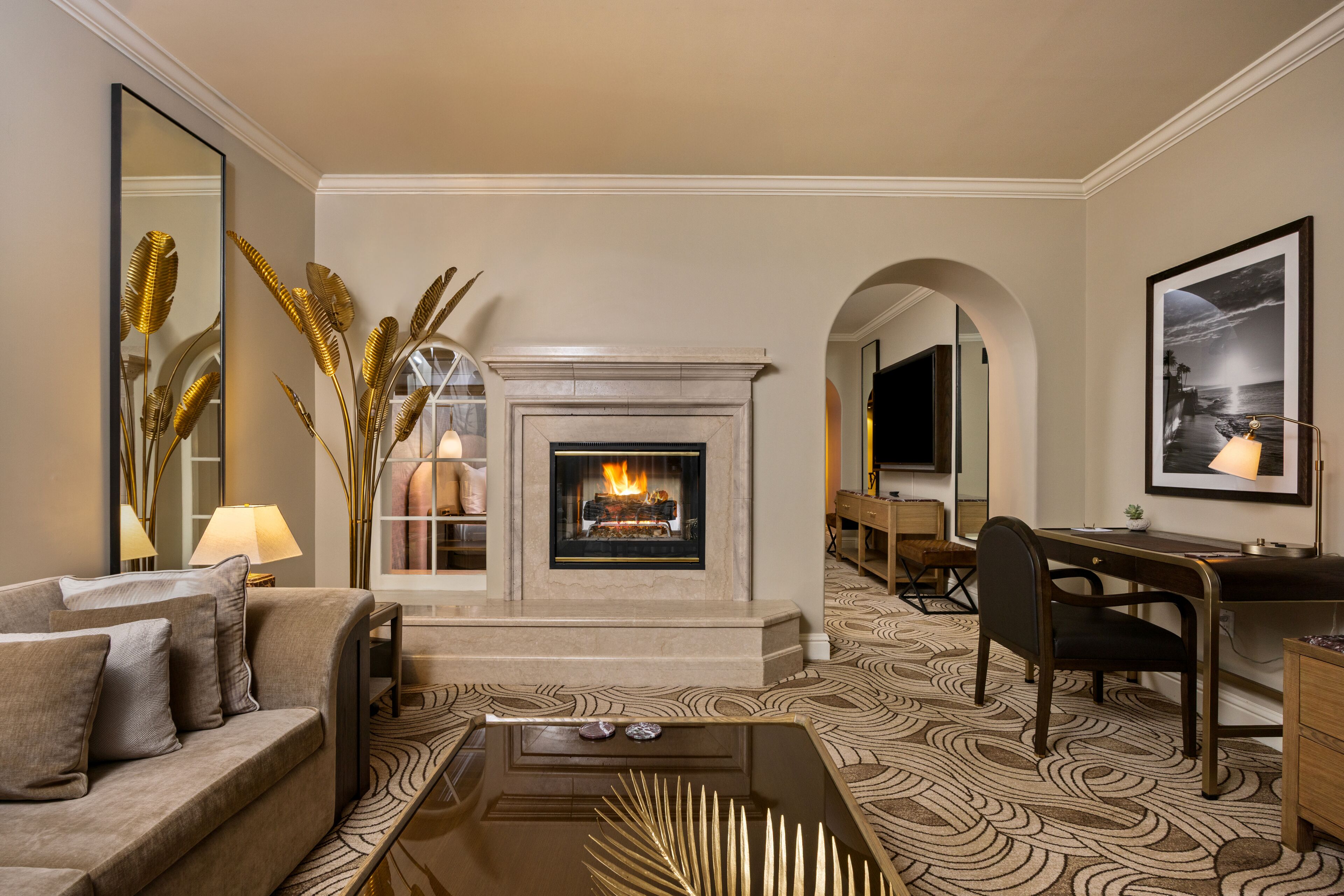 A living room with a fireplace, a sofa, a desk, and a patterned carpet.