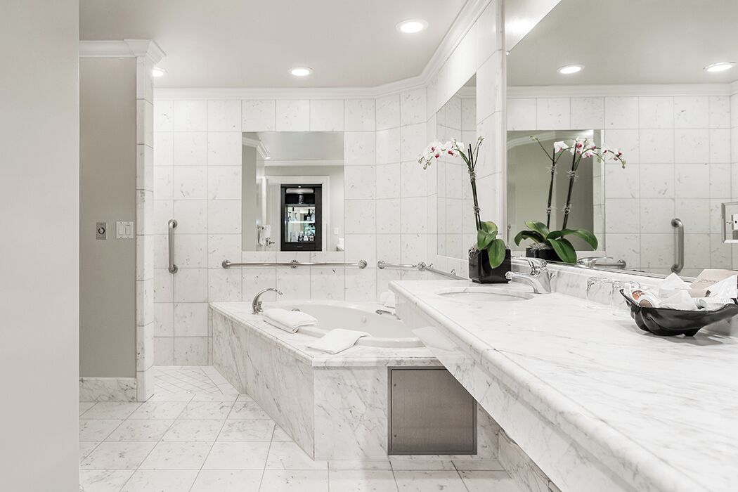 A modern bathroom with a large bathtub, a vanity with a mirror, and a potted orchid.