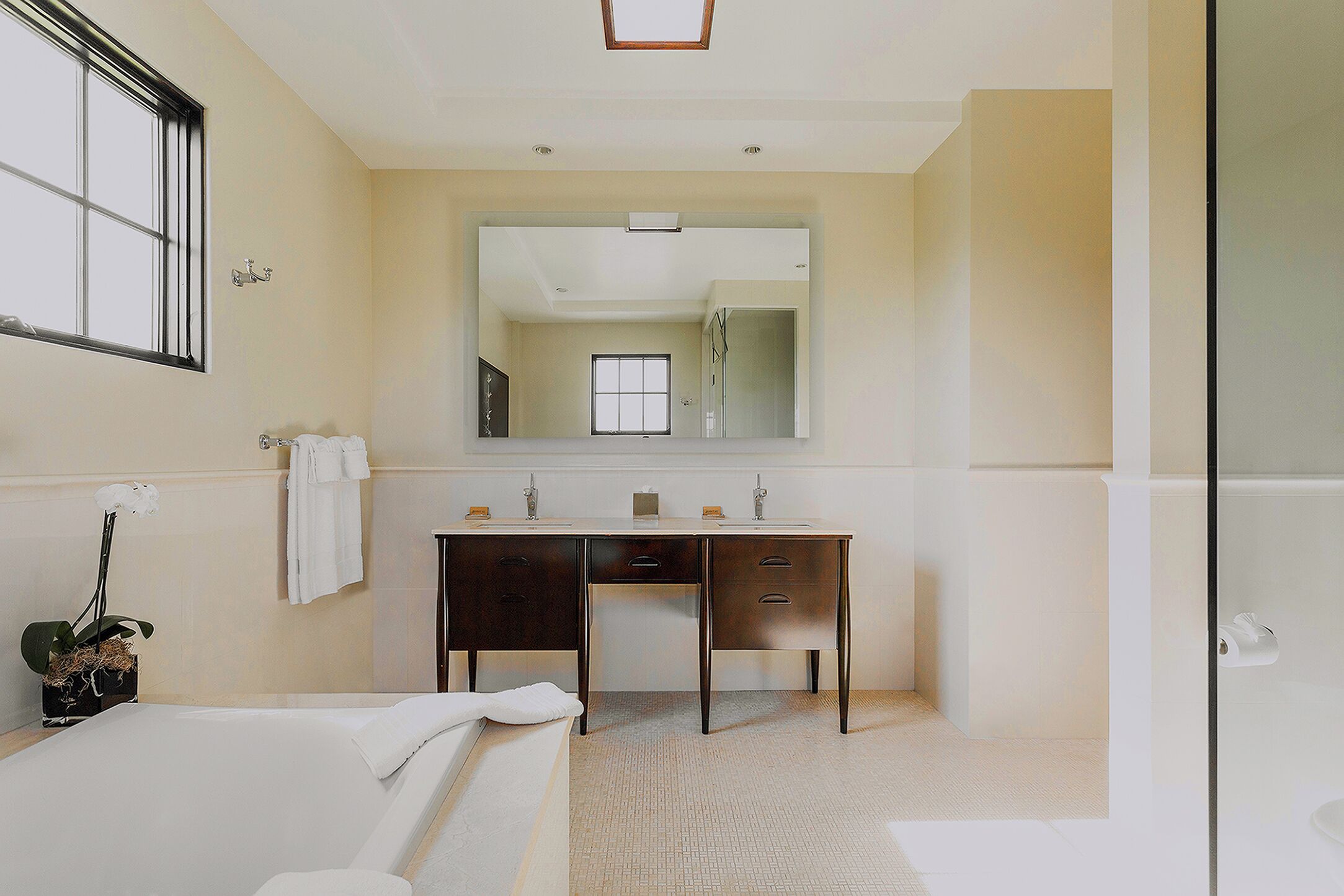 Une salle de bain moderne avec une baignoire, un meuble-lavabo avec un miroir et une fenêtre.