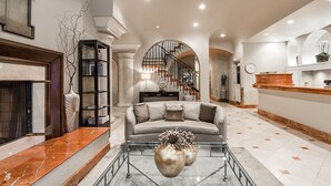 A spacious living area with a fireplace, a sofa, and a coffee table. There is a staircase leading to an upper level. - Montecito Inn (Santa Barbara)