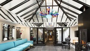 A spacious interior with a high ceiling, a central chandelier, a blue sofa, and a fireplace. - Hotel Louvre Saint Honoré (Paris)