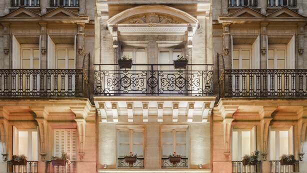 A hotel facade with a central entrance, balconies with wrought iron railings, and flower boxes. - Hotel Louvre Saint Honoré (Paris)