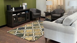 Ein Wohnzimmer mit Flachbildfernseher, dunklem Holzboden, einem gemusterten Teppich, einem grauen Sofa und einer Unterhaltungsecke aus dunklem Holz.