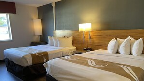 Ein Hotelzimmer mit zwei Betten, einem Nachttisch, einer Lampe und einer Uhr.