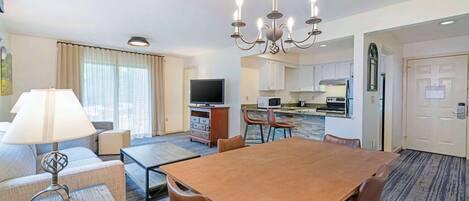 Une chambre d’hôtel avec un coin repas, une kitchenette et un téléviseur.