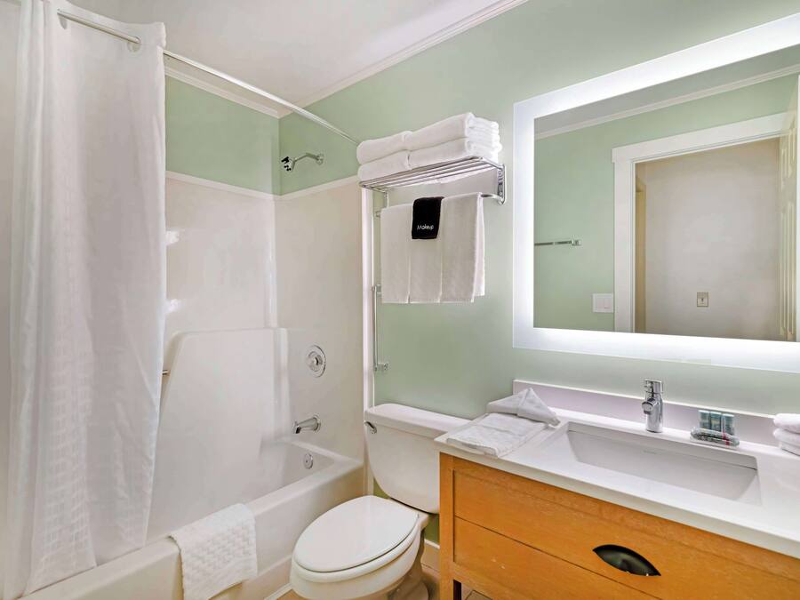A bathroom with a bathtub, toilet, sink, and a large mirror.