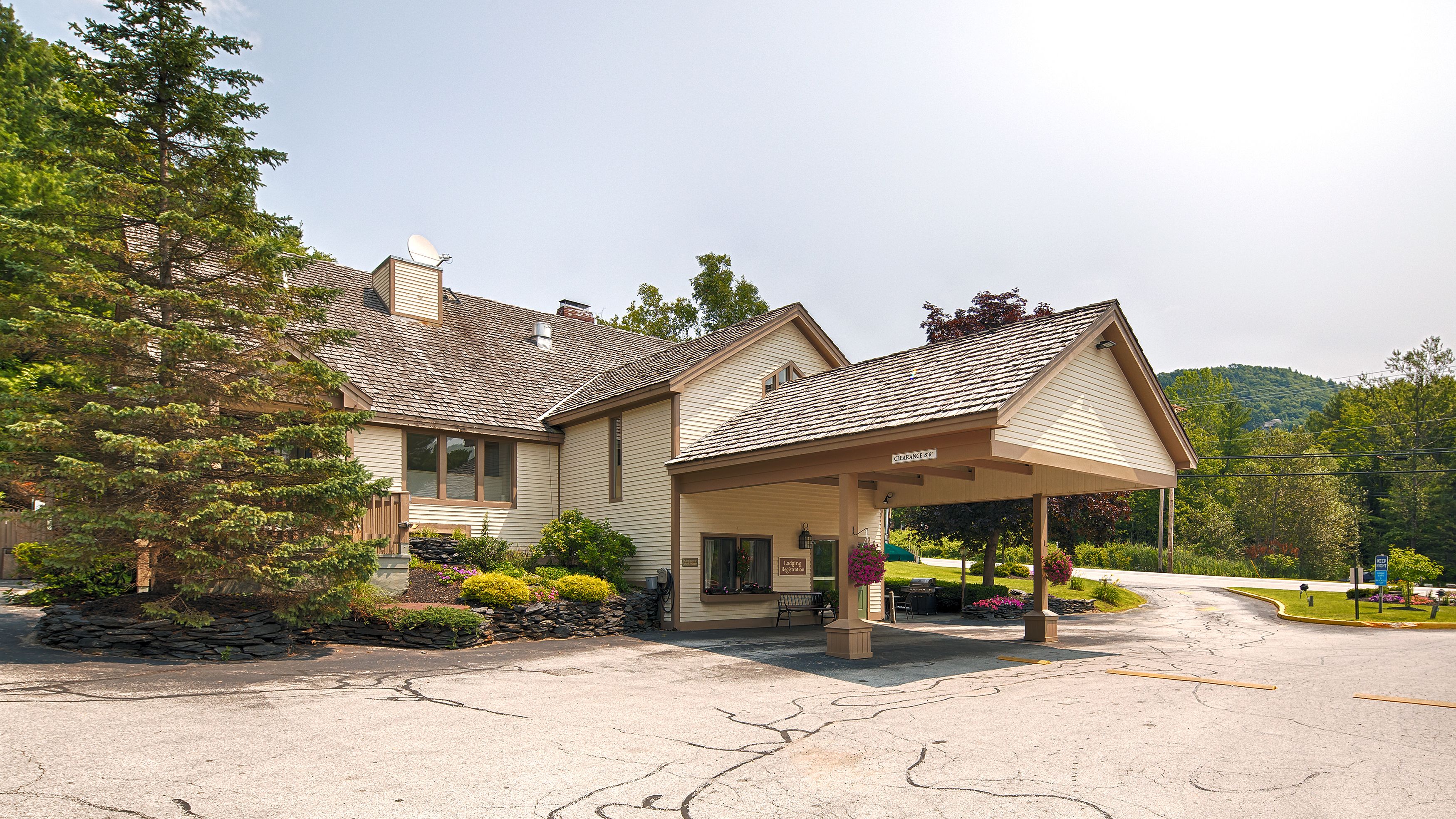 A lodge with a covered entrance, stone wall, and a sign for lodging registration.