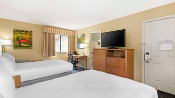 A hotel room with two beds, a desk with a chair, a television, and a wardrobe.