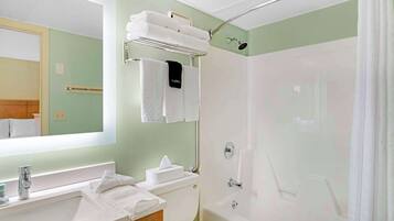 A bathroom with a sink, toilet, and shower. There are towels on the wall and a shelf with more towels.