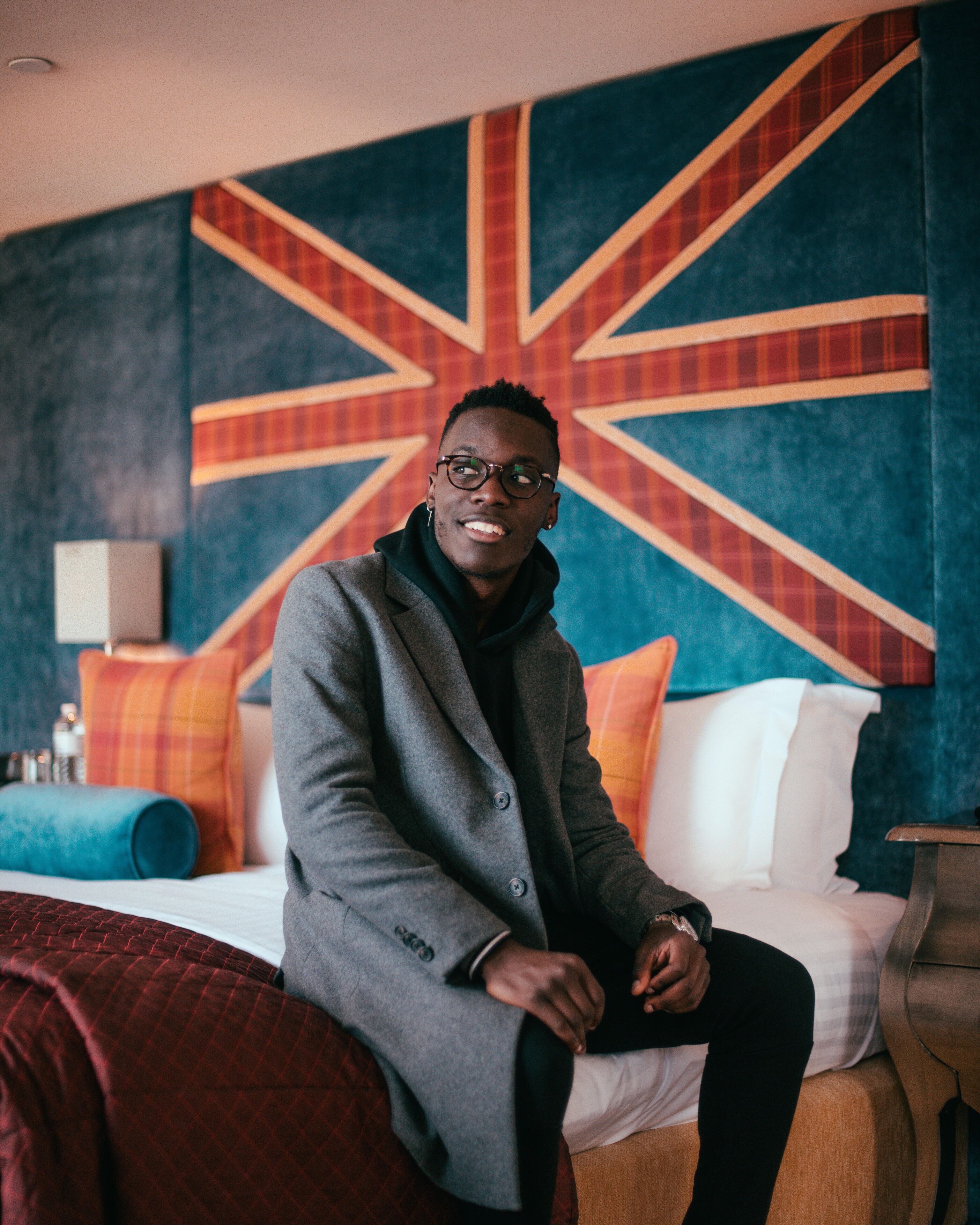 A person sitting on a bed in a hotel room with a large Union Jack wall mural.