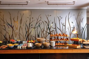 A buffet with various food items and a decorative wall with tree-like patterns.