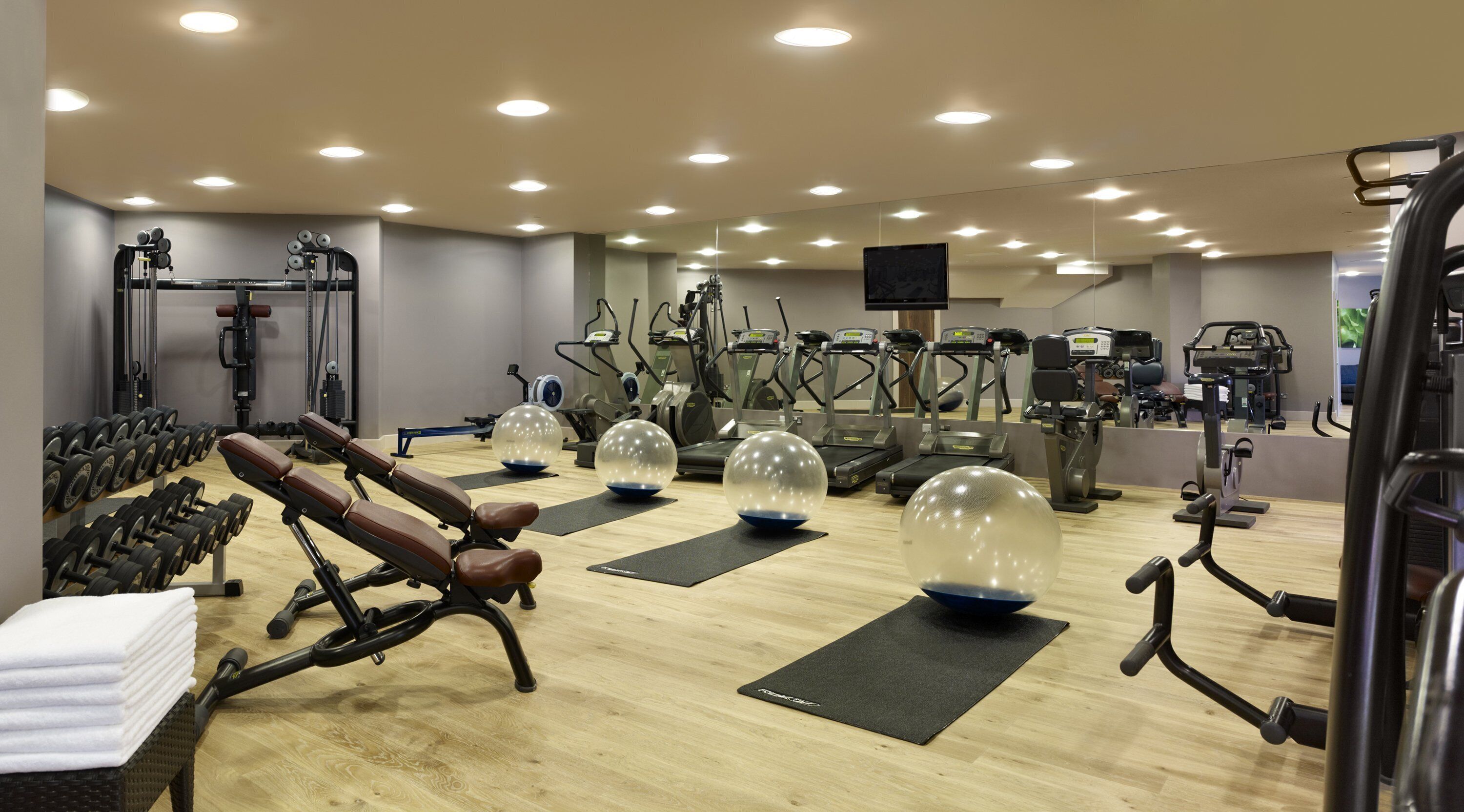 A gym with various exercise equipment, including treadmills, elliptical machines, and free weights.