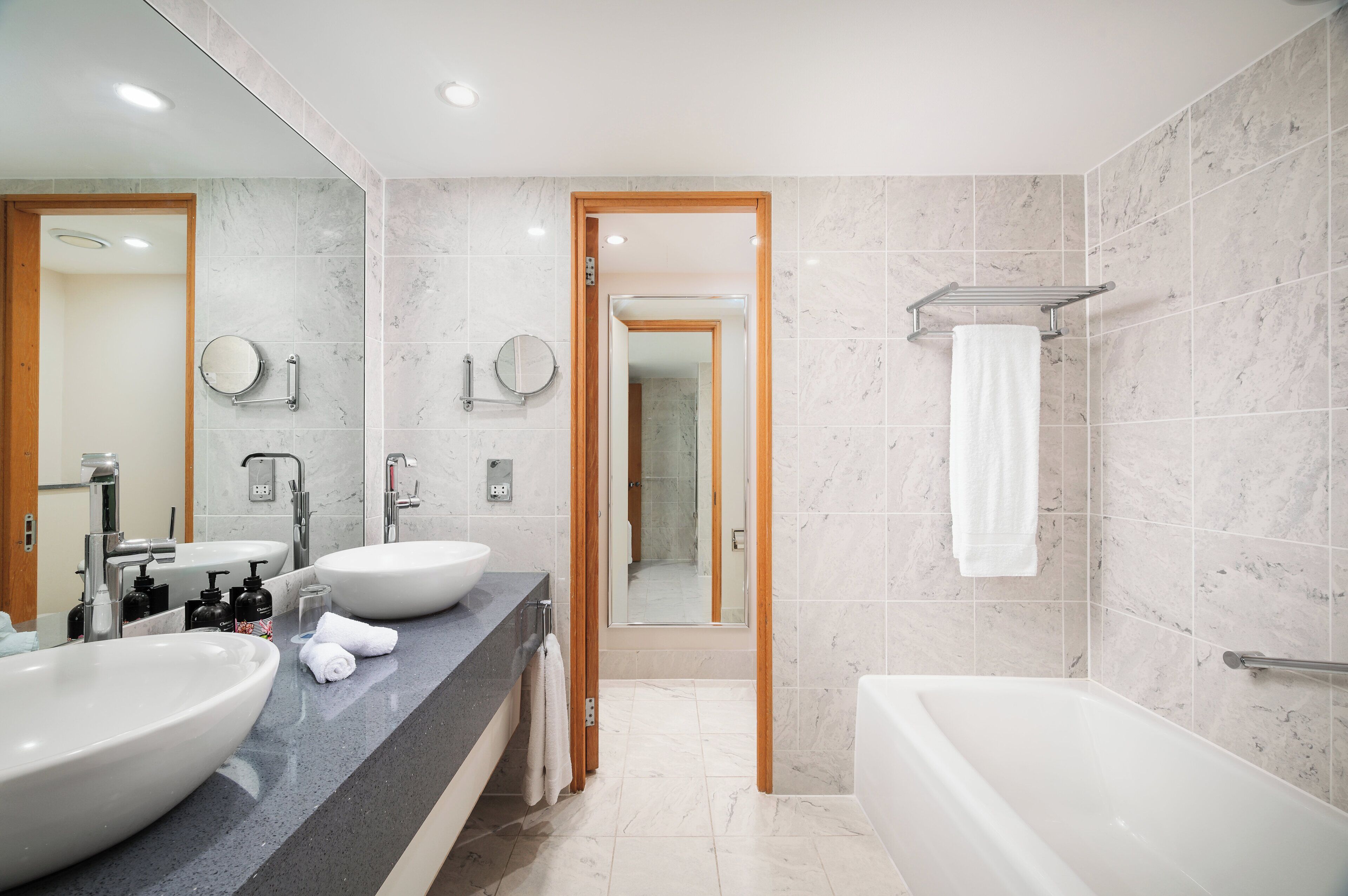 A modern bathroom with two sinks, a bathtub, and a shower.