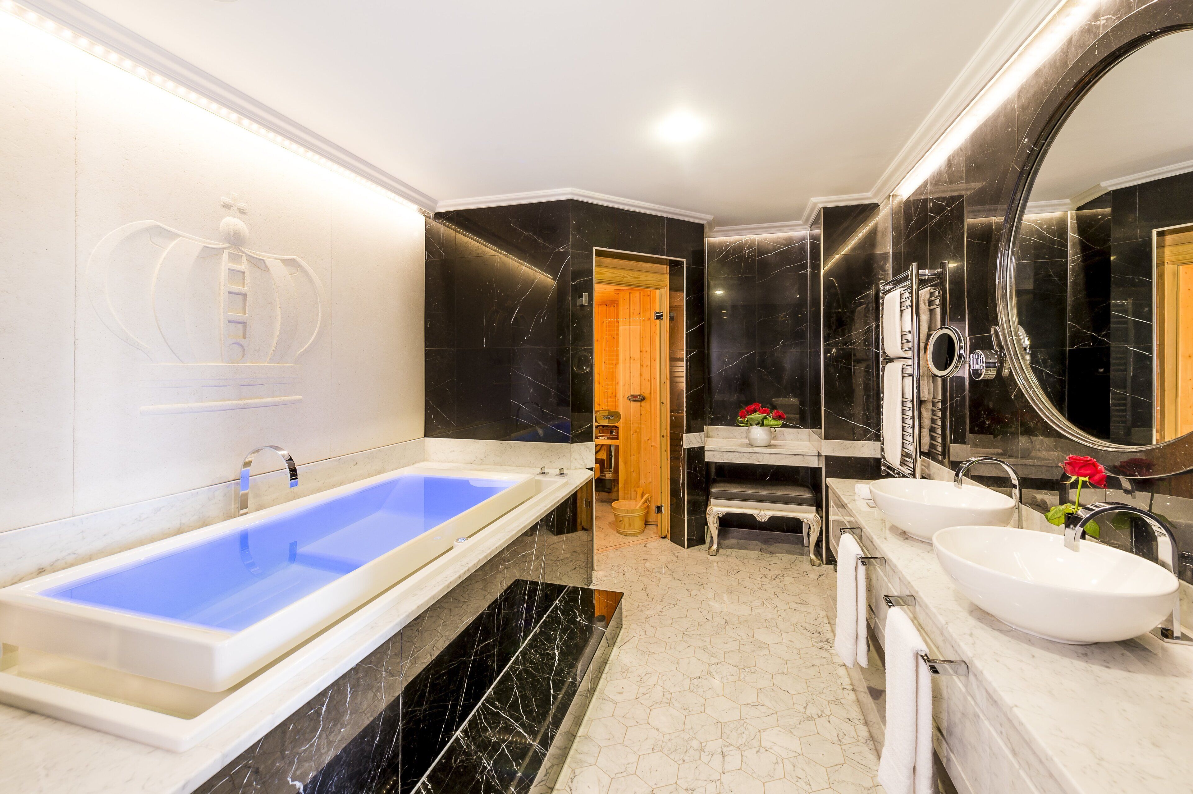 Un baño moderno con una bañera grande, dos lavamanos, un tocador y un espejo amplio.