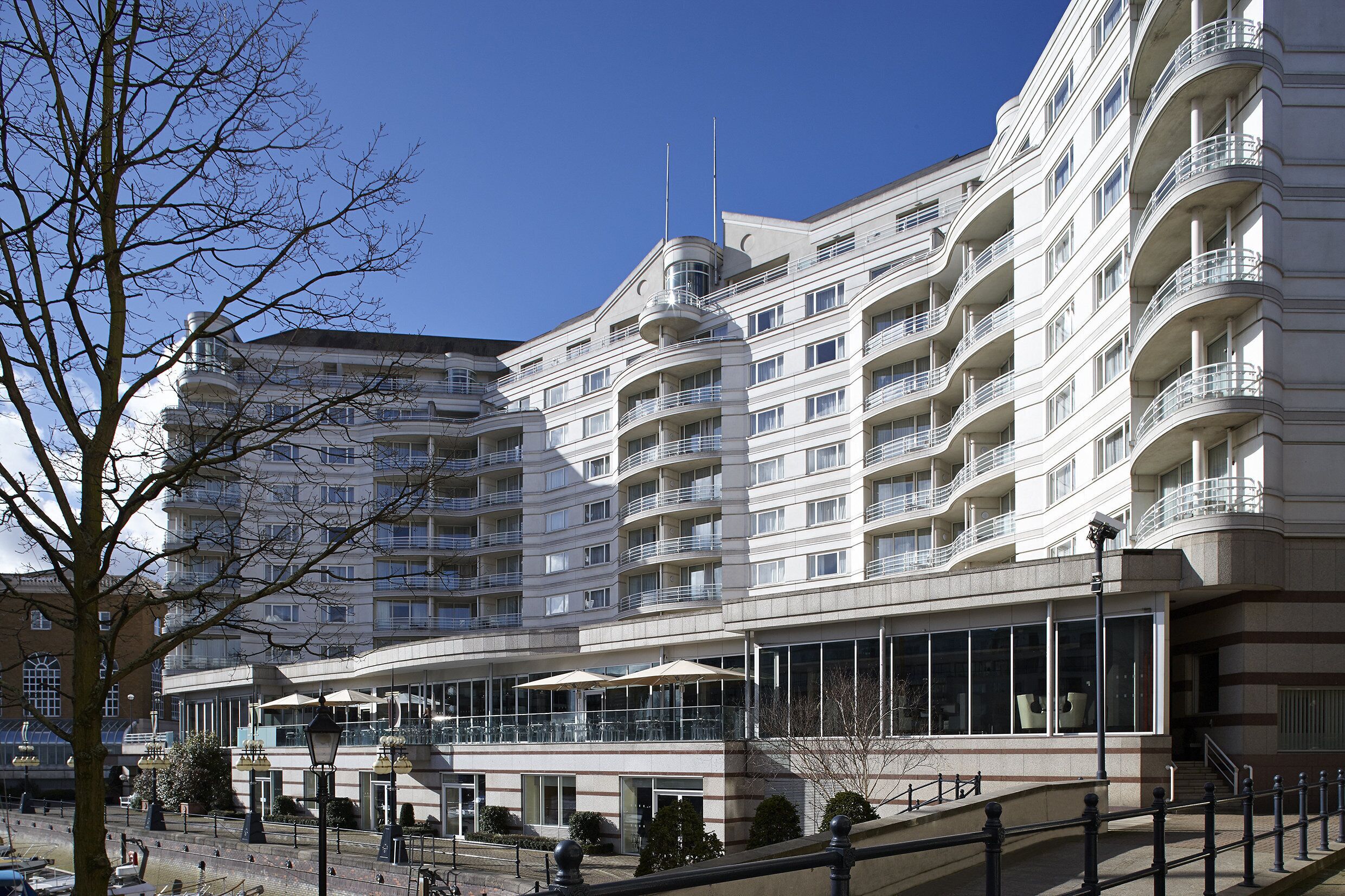 A multi-story hotel with balconies, large windows, and a central courtyard with umbrellas.