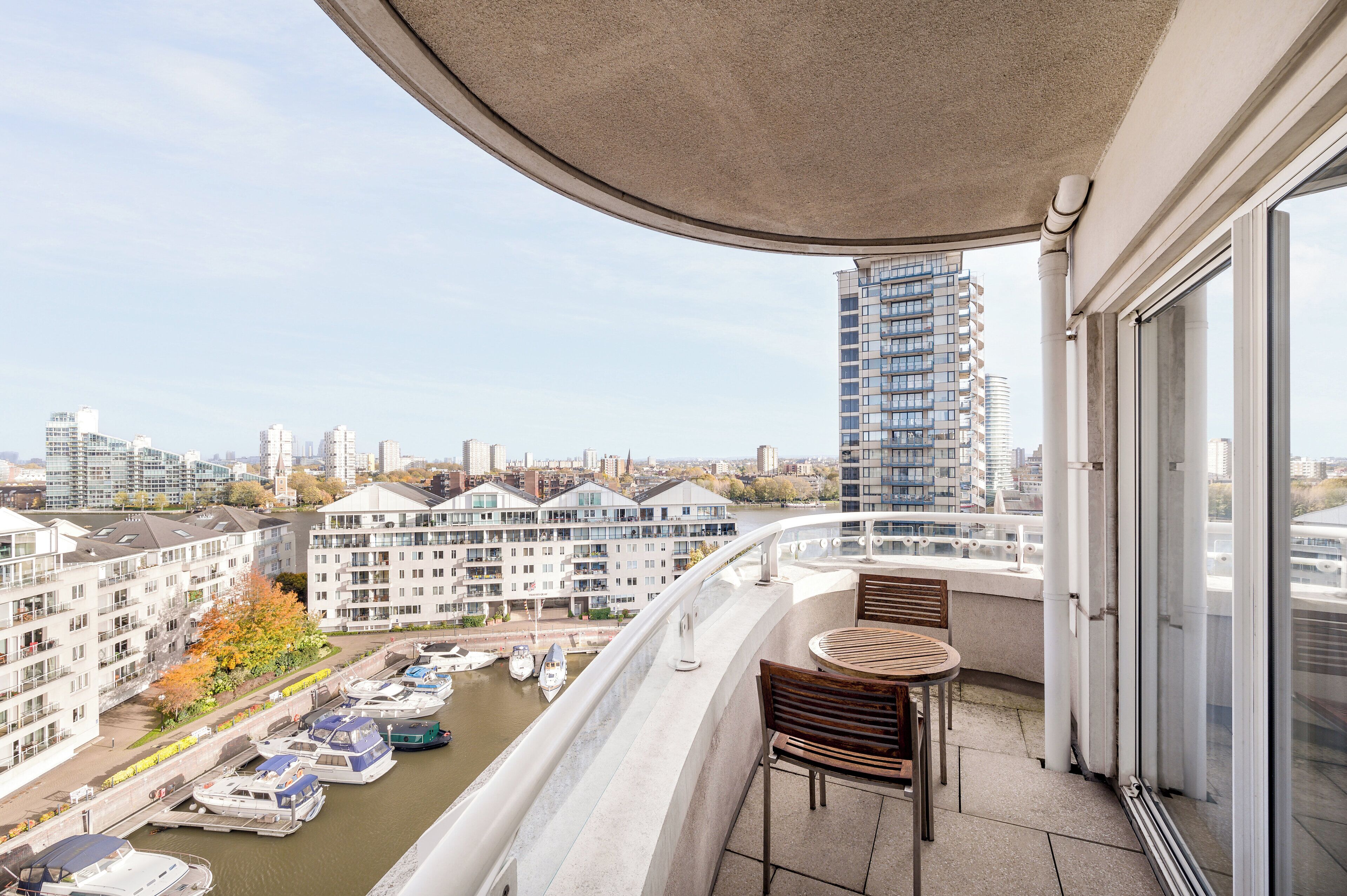 A balcony with a view of a river, boats, and buildings.