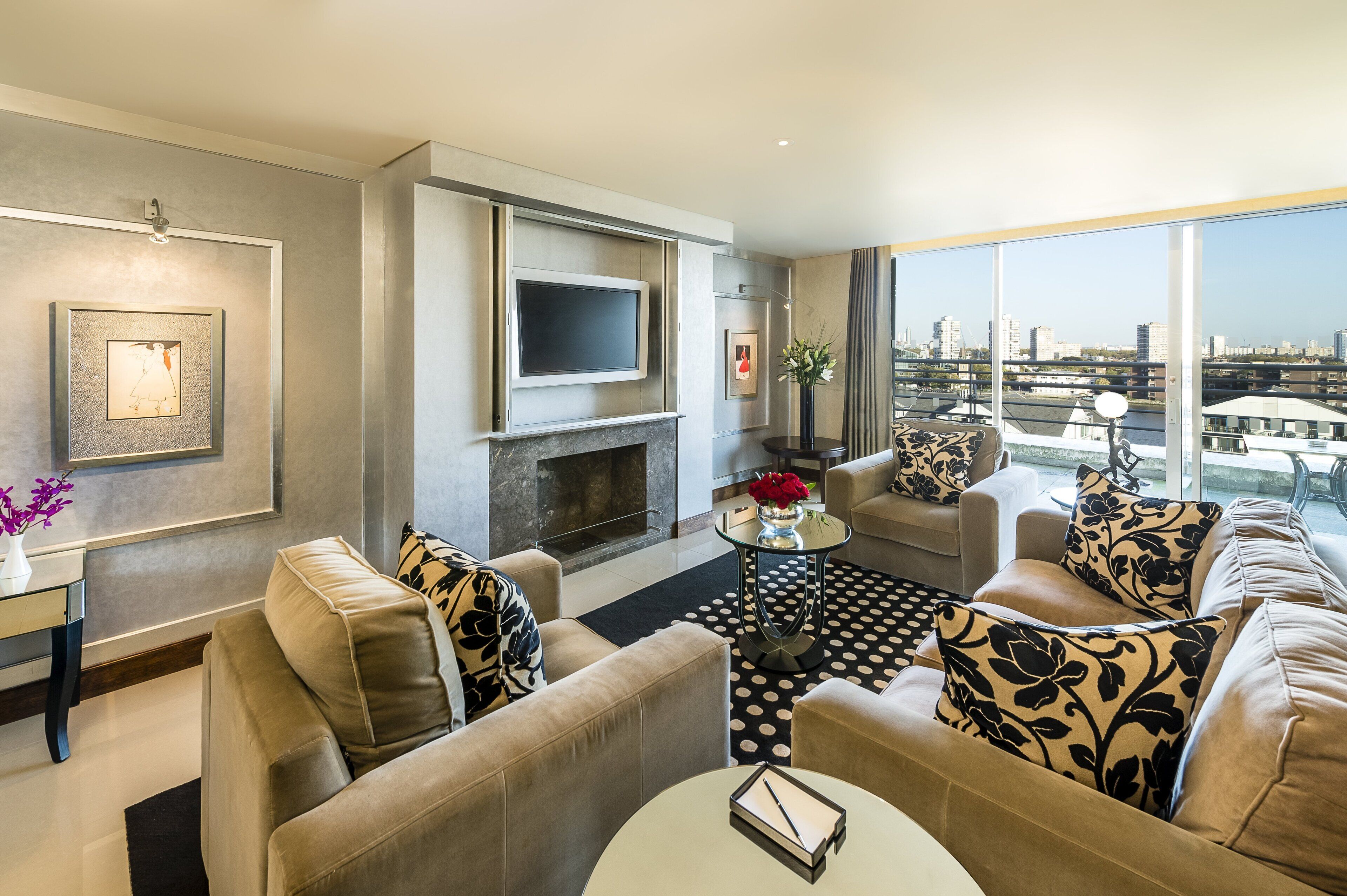 Una sala de estar moderna con chimenea, asientos cómodos, un televisor de pantalla plana y un ventanal con vistas a la ciudad.