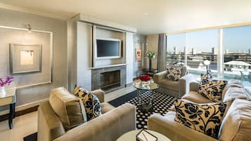 Una sala de estar moderna con chimenea, asientos cómodos, un televisor de pantalla plana y un ventanal con vistas a la ciudad.
