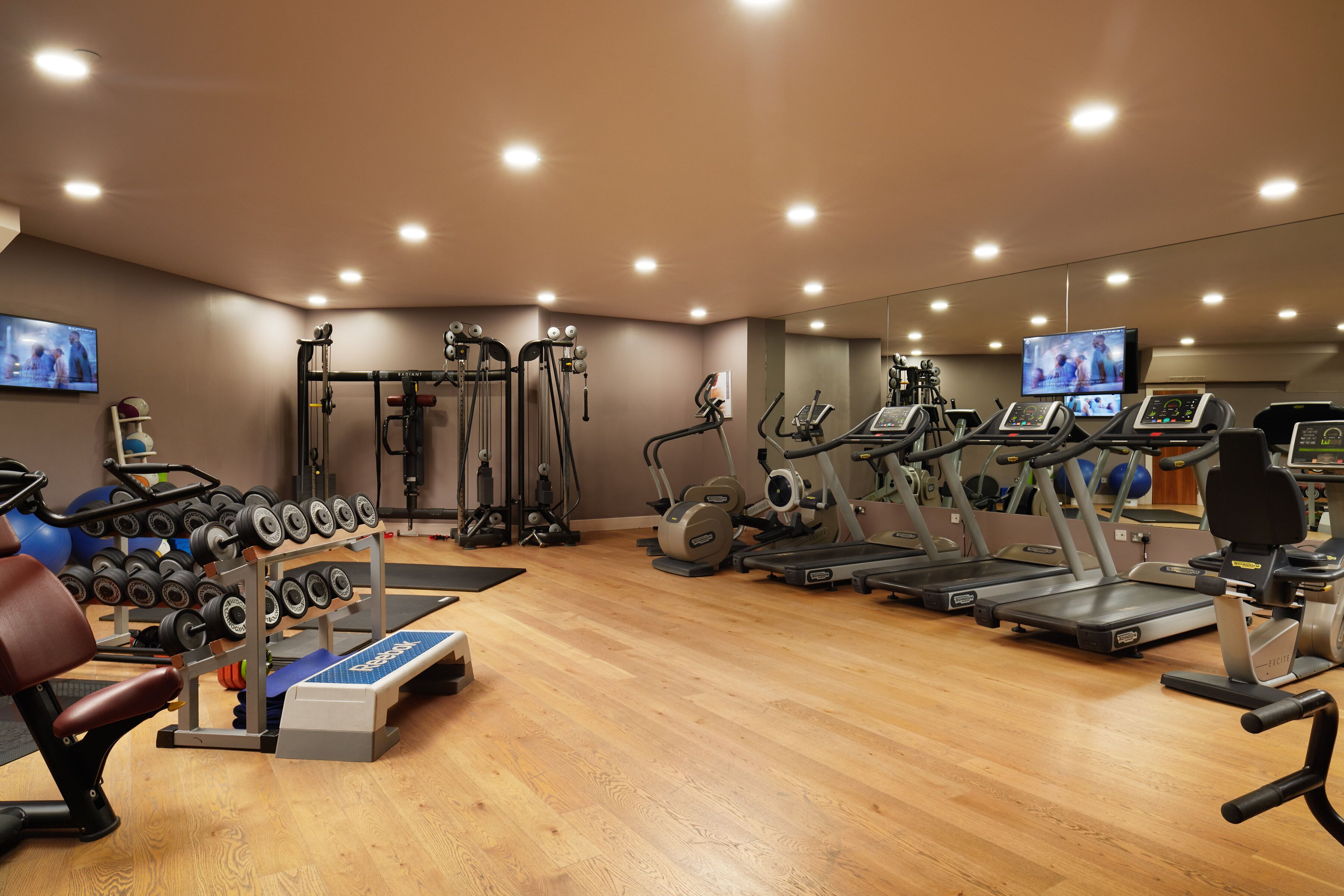 A gym with treadmills, weight machines, and a rowing machine.
