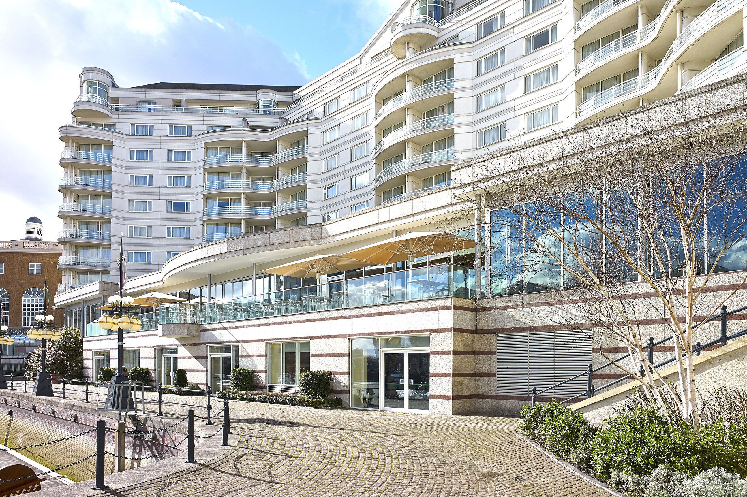 A multi-story hotel with balconies, a covered outdoor seating area, and a brick pathway.