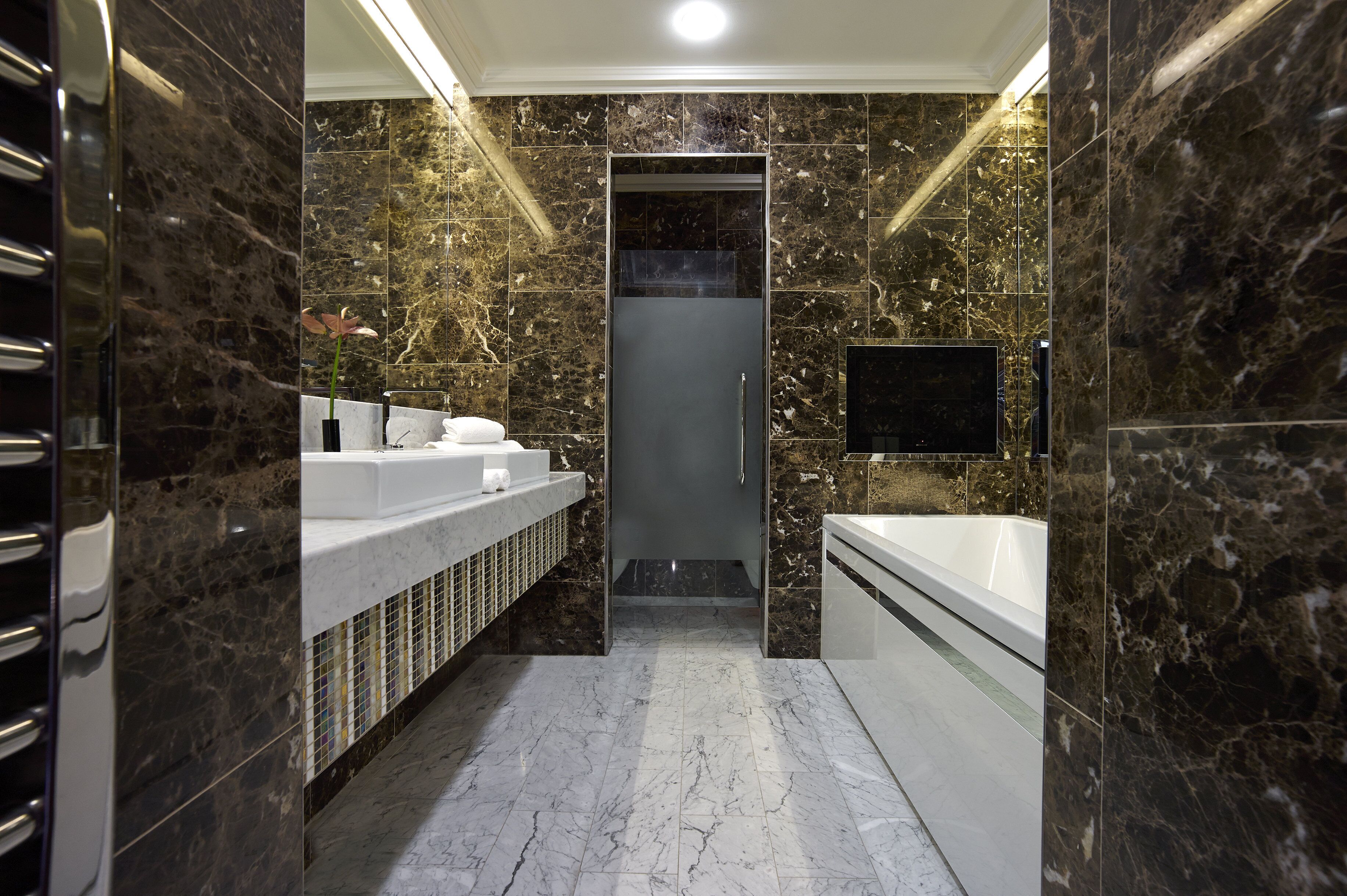 A modern bathroom with a marble floor, a large bathtub, a sink, and a toilet.