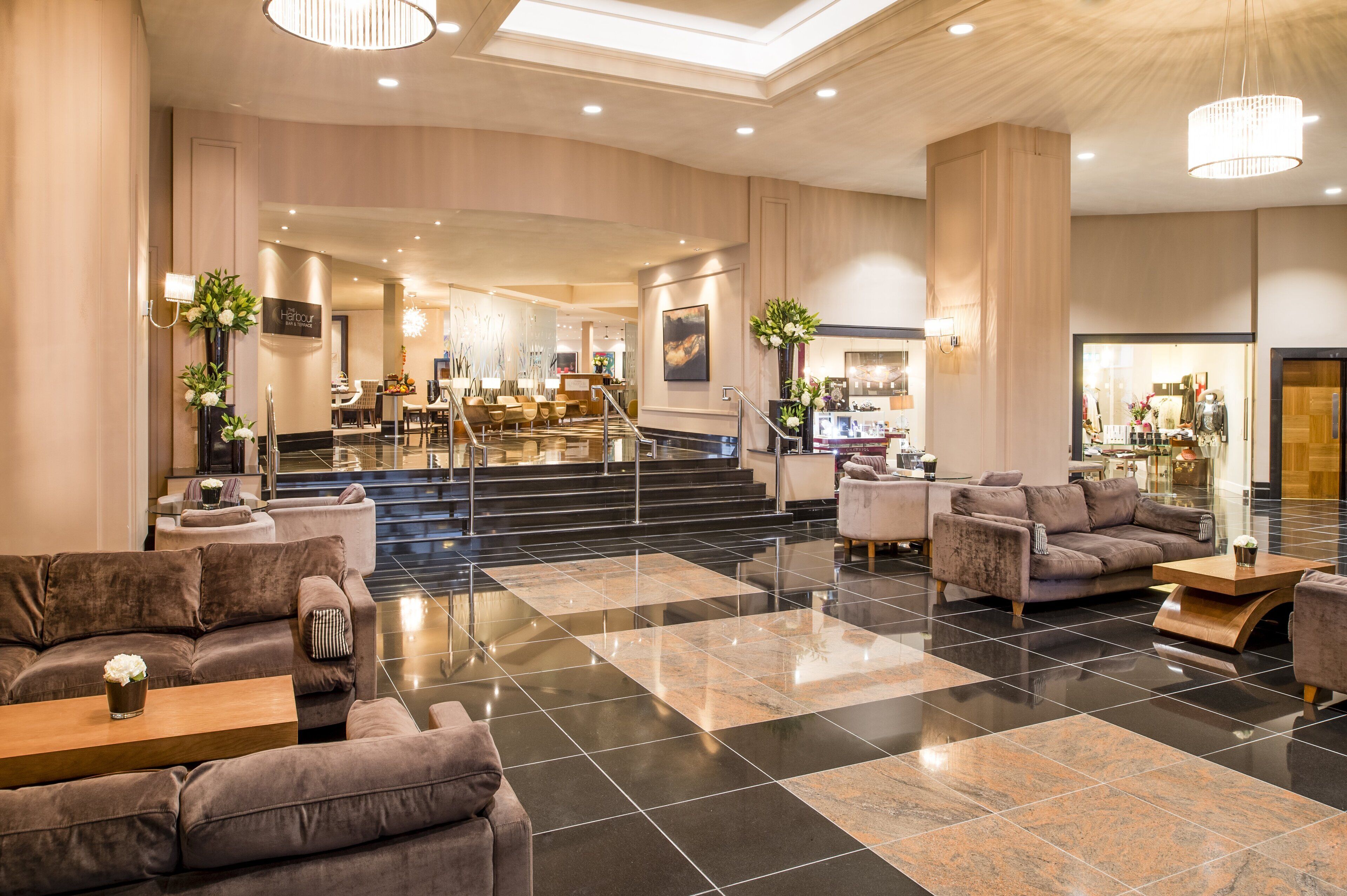 A spacious lobby with a central staircase, seating areas, and a reception desk.