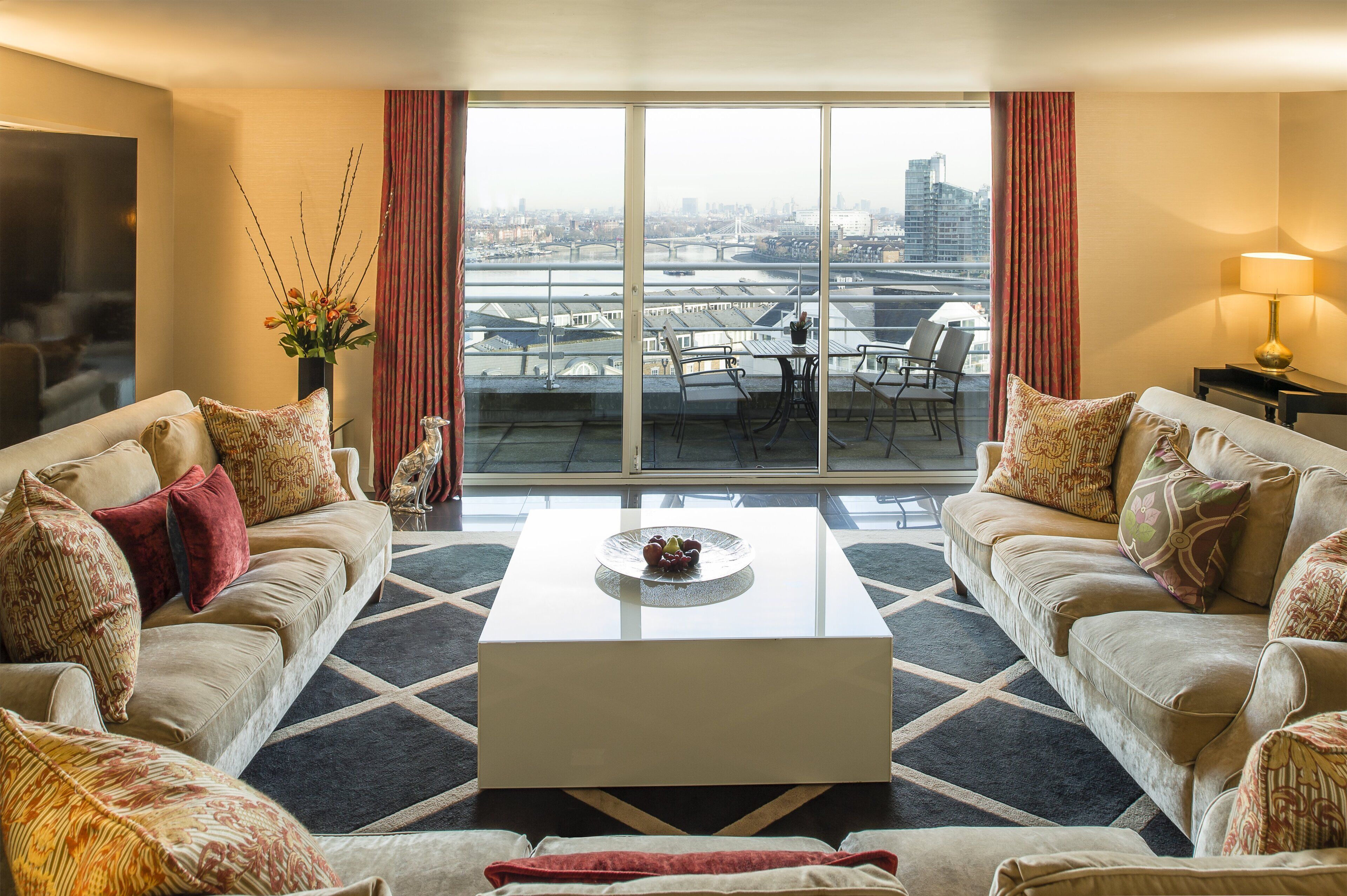 A modern living room with two sofas, a coffee table, and a view of a cityscape through large windows.