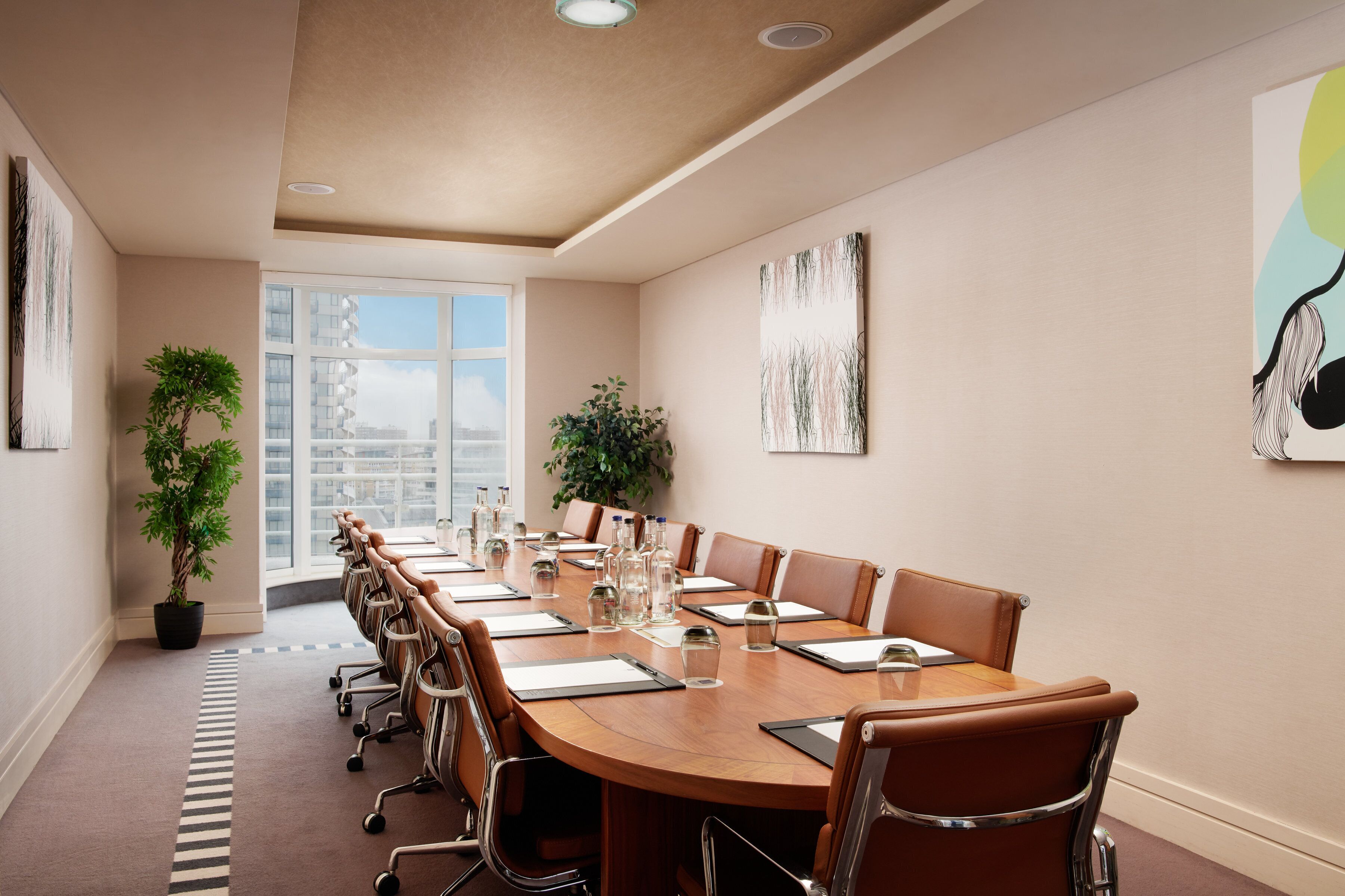 Une salle de conférence avec une longue table, des chaises et des plantes en pot.