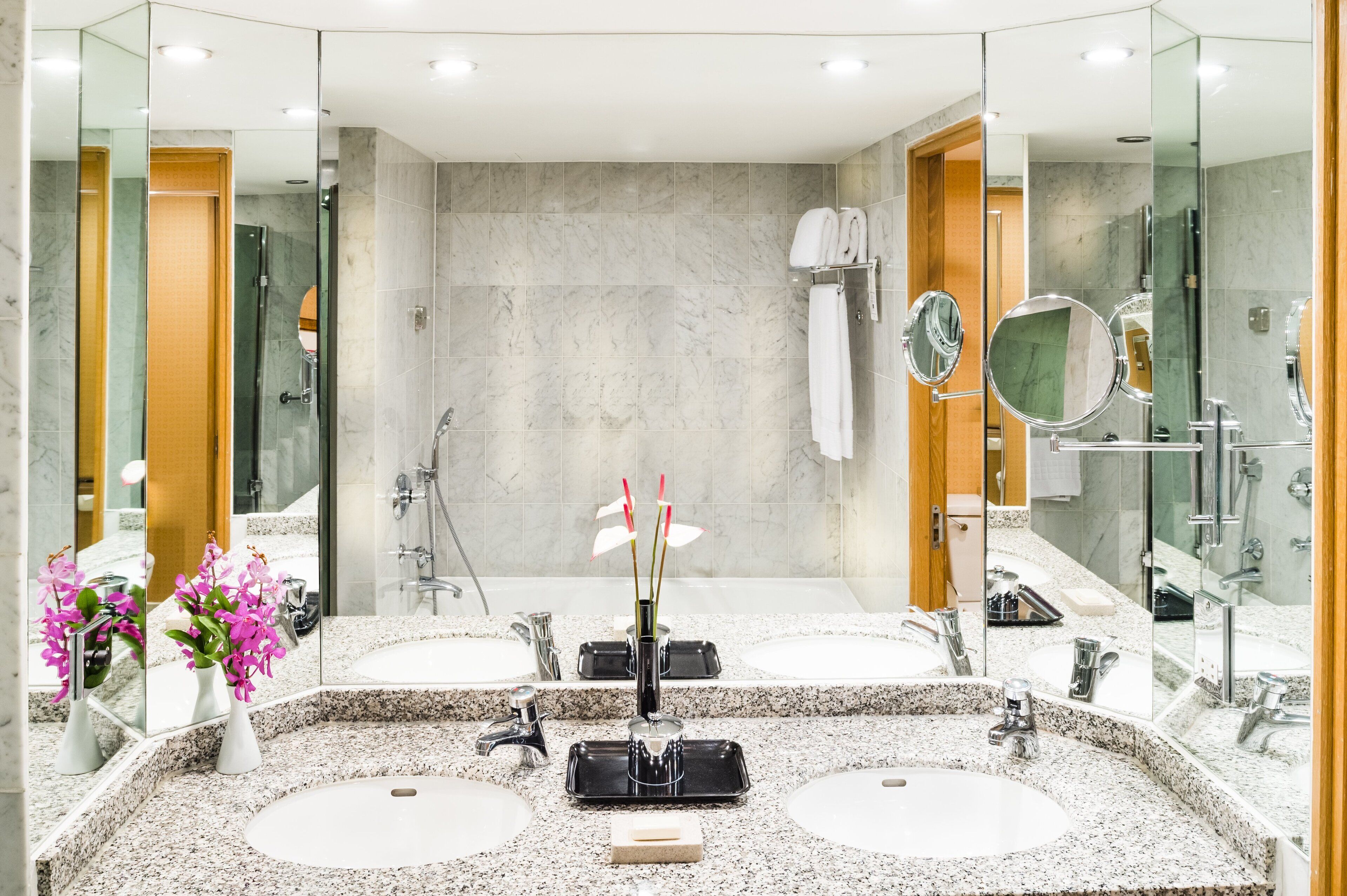 A modern bathroom with two sinks, a shower, and a large mirror.