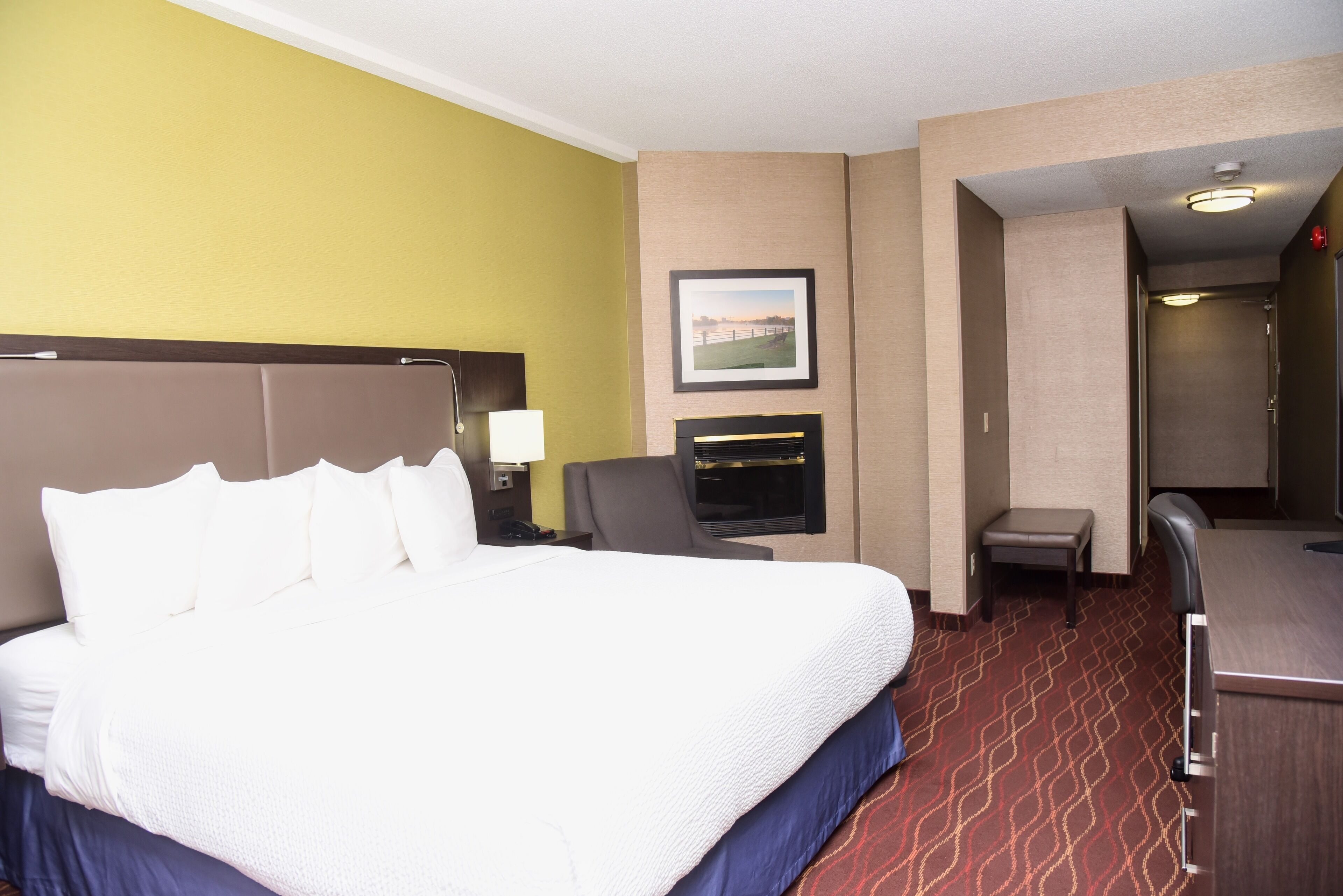 Una habitación de hotel con una cama grande, un escritorio, una silla, un televisor y una mesita.