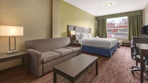 Ein Hotelzimmer mit einer Couch, einem Bett, einem Schreibtisch und einem Fernseher.