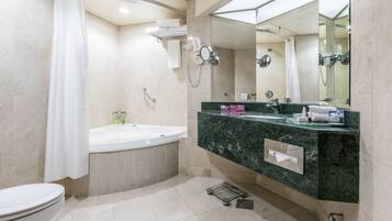 Un baño moderno con bañera, ducha, inodoro y tocador con espejo.