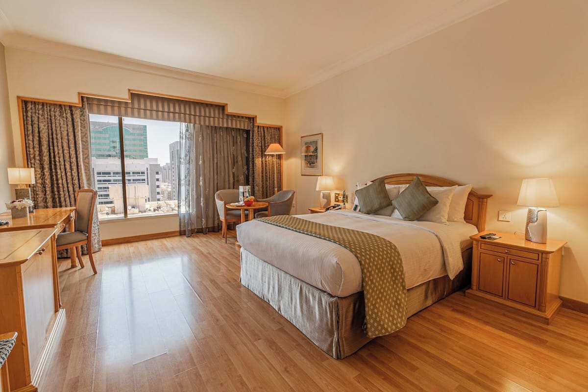 Een hotelkamer met een groot bed, een bureau, een stoel en uitzicht op de stad.