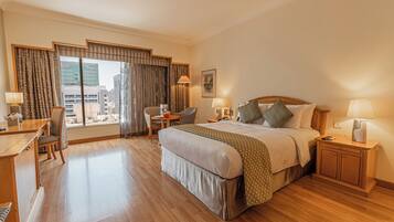 Quarto de hotel com uma cama grande, uma escrivaninha, uma cadeira e vista para a cidade.