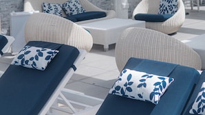 A rooftop lounge area with wicker furniture, a flat-screen TV, and a city view.