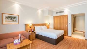 Une chambre d’hôtel avec un lit, une table de chevet, un plancher en bois, un canapé et un tableau encadré au mur.