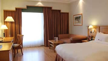 A hotel room with a bed, a desk, a chair, a sofa, and a small table.