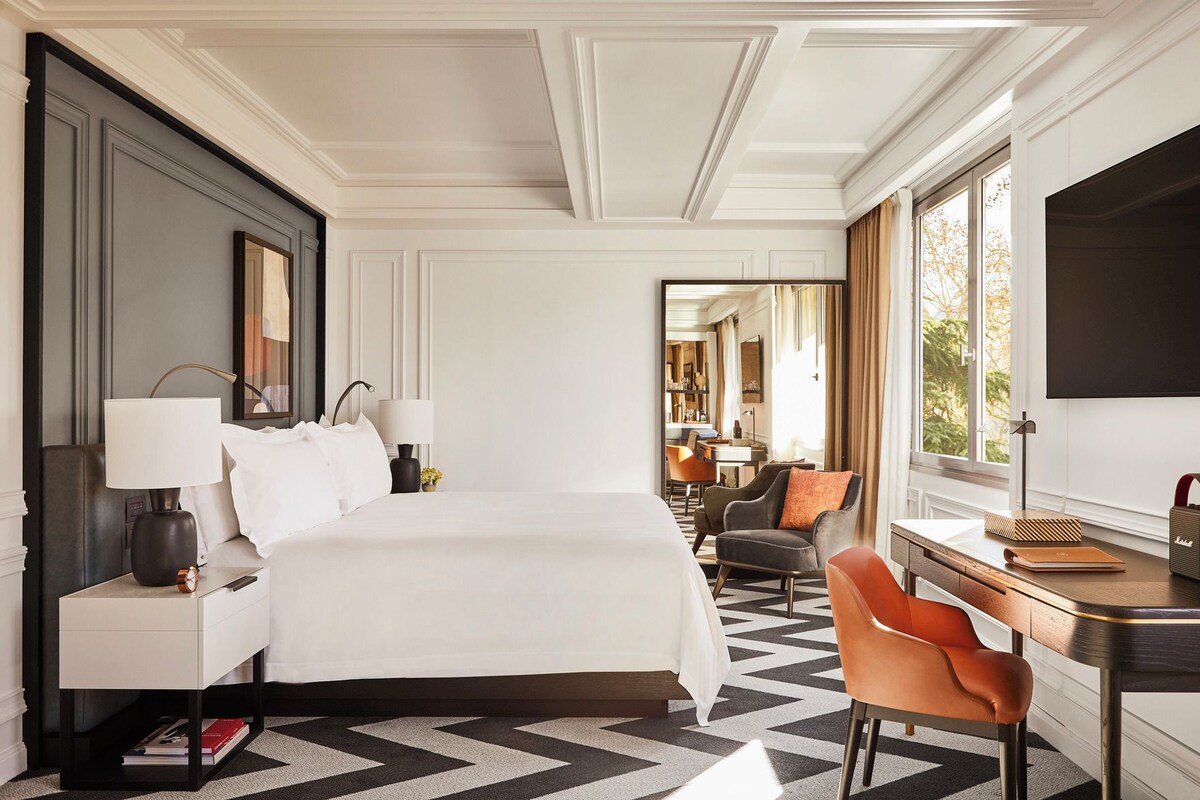 Una habitación de hotel con una cama grande, un escritorio, una silla y un televisor.