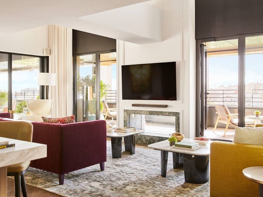 Un salon moderne doté d’un grand téléviseur, de sièges confortables et de grandes fenêtres offrant une vue sur la ville.
