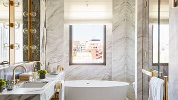 Un baño moderno con una bañera independiente, un espejo grande y una ventana que ofrece vistas a la ciudad.