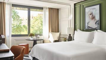 Habitación de hotel con una cama grande, un escritorio, una silla y vistas al exterior.