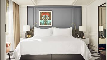 Hotelkamer met een groot bed, twee nachtkastjes met lampen, een lijst met kunstwerk aan de muur en een spiegel aan de overkant.
