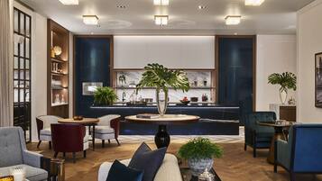 A modern living room with a sofa, chairs, a coffee table, and a kitchen area in the background.