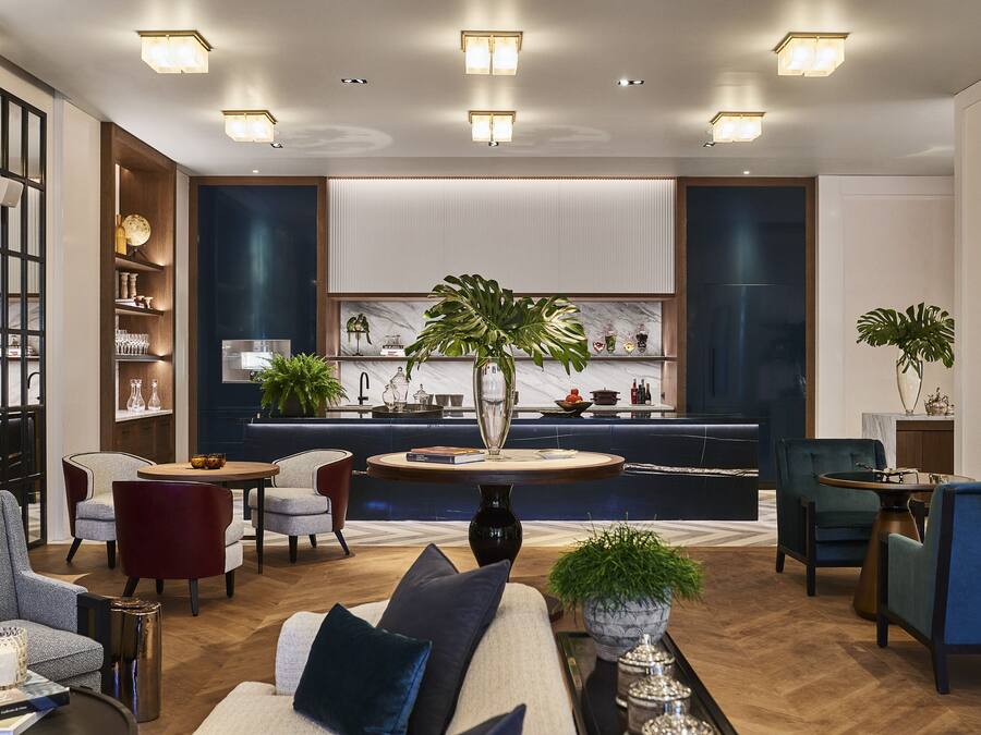 A modern living room with a sofa, chairs, a coffee table, and a kitchen area in the background.