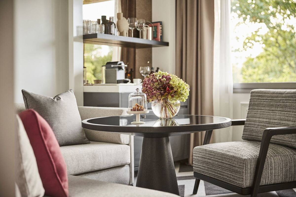 A modern living room with a round glass table, a sofa, and a chair.